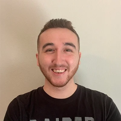 Chiropractor Dillan Van Ness Smiling In Front Of Beige Wall